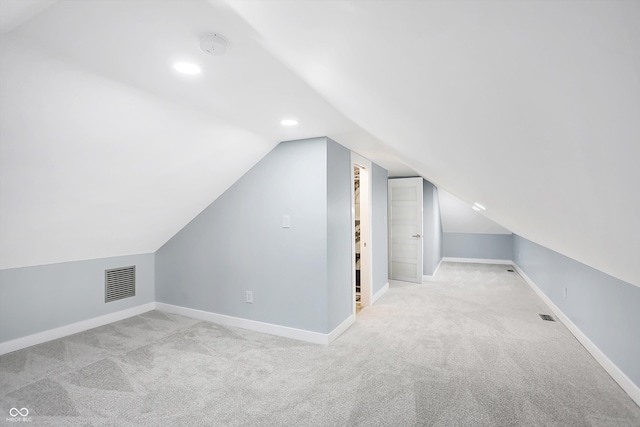 additional living space featuring light colored carpet and vaulted ceiling