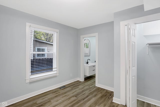 unfurnished bedroom featuring wood-type flooring, a closet, and connected bathroom