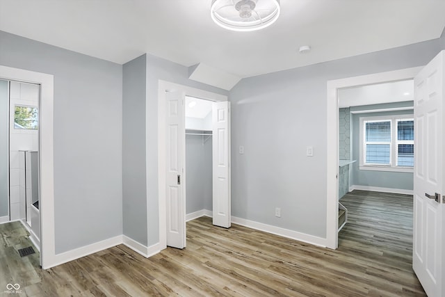 unfurnished bedroom with wood-type flooring, lofted ceiling, and multiple windows