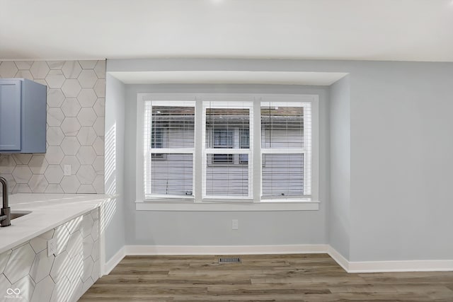 unfurnished dining area with hardwood / wood-style flooring, sink, and a wealth of natural light