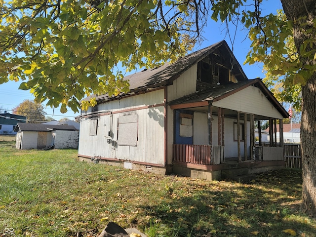 view of side of property with a porch, a storage unit, and a yard