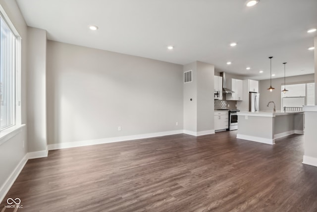 unfurnished living room with sink, dark hardwood / wood-style flooring, and plenty of natural light