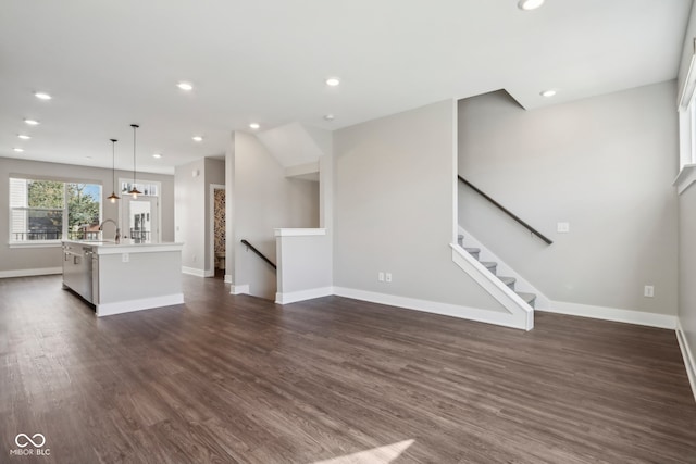 unfurnished living room featuring an inviting chandelier, dark hardwood / wood-style floors, and sink