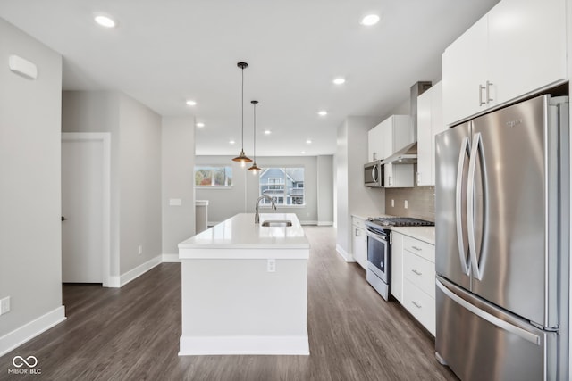 kitchen with a kitchen island with sink, dark wood-type flooring, hanging light fixtures, stainless steel appliances, and white cabinets