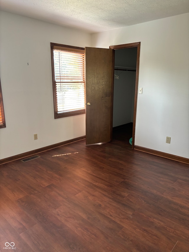 unfurnished bedroom with dark wood-type flooring and a textured ceiling