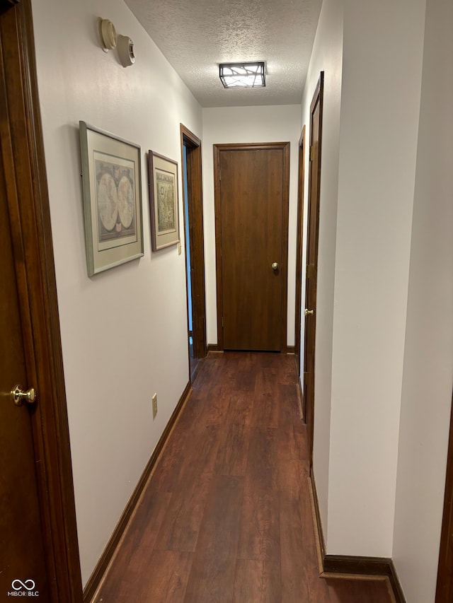 hall featuring dark wood-type flooring and a textured ceiling