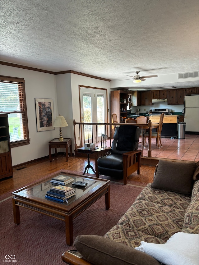 living room featuring french doors, a textured ceiling, ceiling fan, tile patterned floors, and ornamental molding