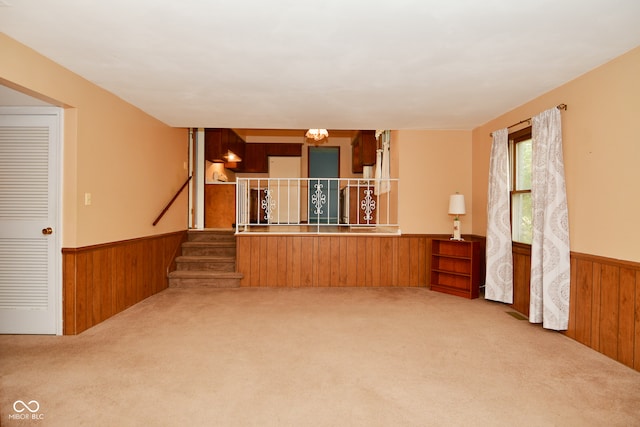 unfurnished room featuring an inviting chandelier, wooden walls, and carpet