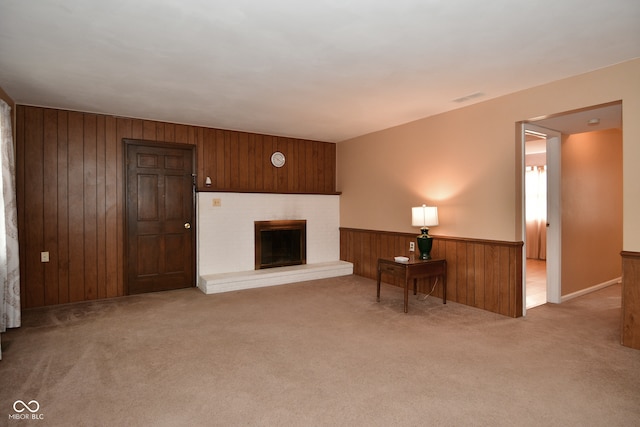 unfurnished living room featuring wood walls, a fireplace, and light colored carpet