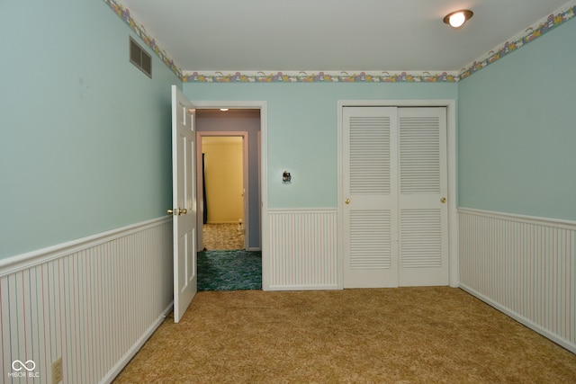 unfurnished bedroom featuring light carpet and a closet