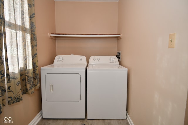 laundry room featuring light hardwood / wood-style flooring, washer and dryer, and a healthy amount of sunlight