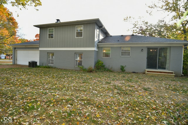 back of house featuring a yard, central AC unit, and a garage