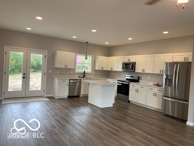 kitchen with pendant lighting, appliances with stainless steel finishes, white cabinets, and dark hardwood / wood-style flooring