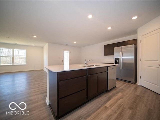 kitchen with sink, hardwood / wood-style flooring, an island with sink, appliances with stainless steel finishes, and dark brown cabinets