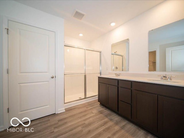 bathroom featuring hardwood / wood-style flooring, vanity, and a shower with door