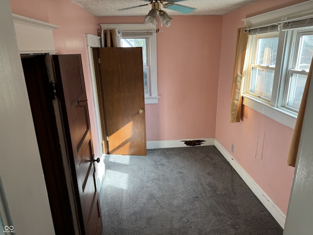 empty room with ceiling fan, a textured ceiling, and carpet floors