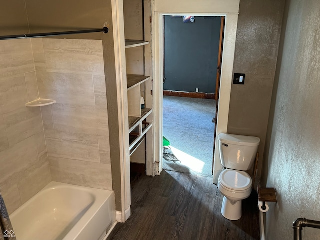 bathroom with tiled shower / bath, hardwood / wood-style flooring, and toilet