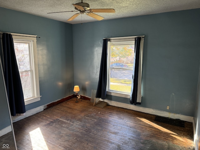 spare room featuring dark wood-type flooring, ceiling fan, and a textured ceiling