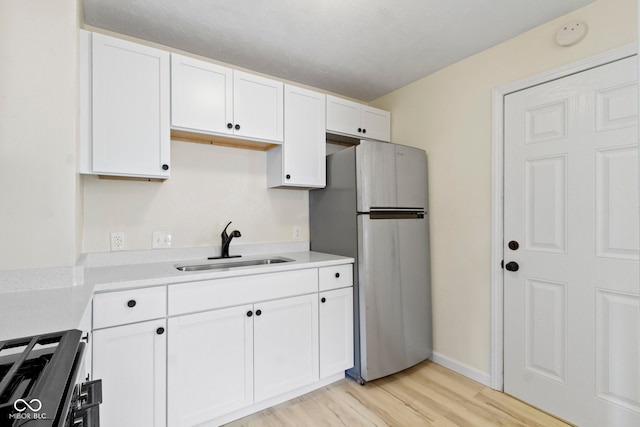 kitchen with sink, white cabinetry, light hardwood / wood-style flooring, and stainless steel appliances