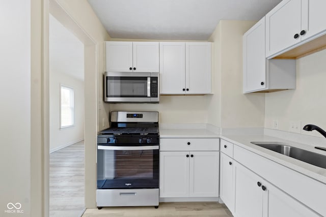 kitchen featuring light hardwood / wood-style flooring, appliances with stainless steel finishes, sink, and white cabinets