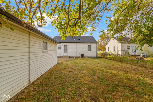 rear view of property featuring a yard and central air condition unit