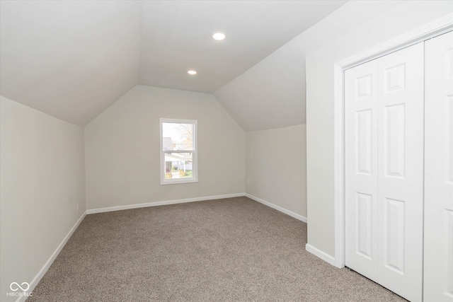 additional living space with light colored carpet and vaulted ceiling