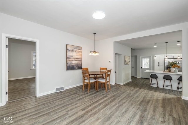 dining area featuring dark hardwood / wood-style flooring and an inviting chandelier