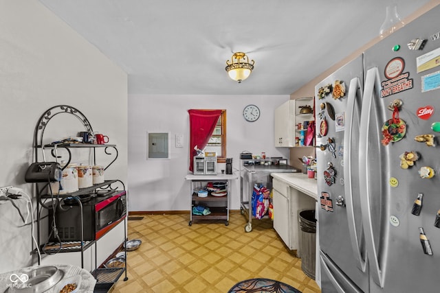 kitchen with white cabinetry, stainless steel refrigerator, and electric panel