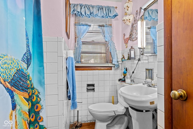 bathroom featuring tile walls, sink, a shower with curtain, and toilet