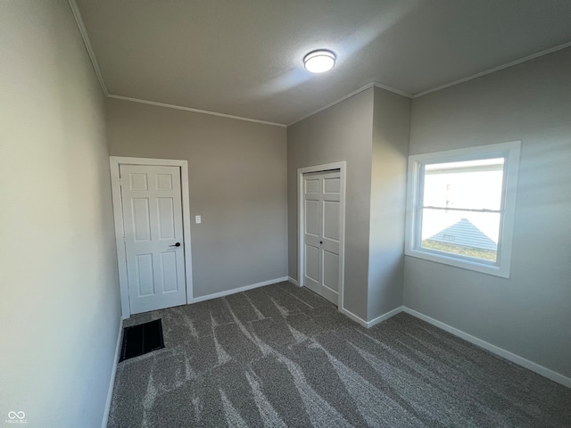 unfurnished bedroom with a closet, ornamental molding, and dark carpet