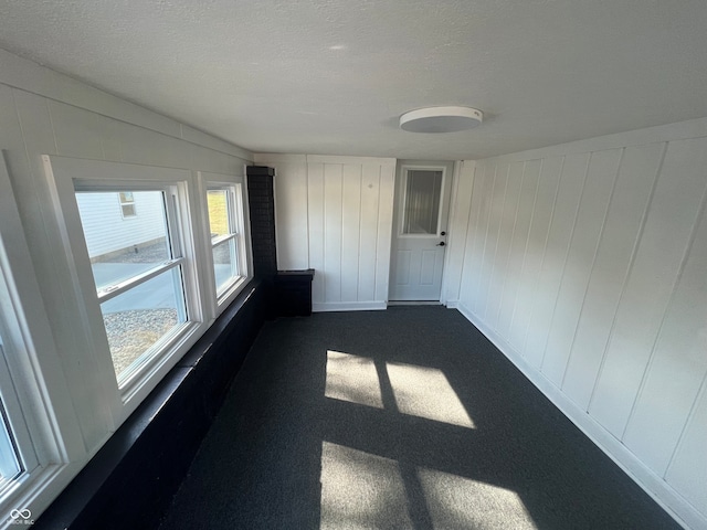 carpeted empty room featuring wood walls and a textured ceiling