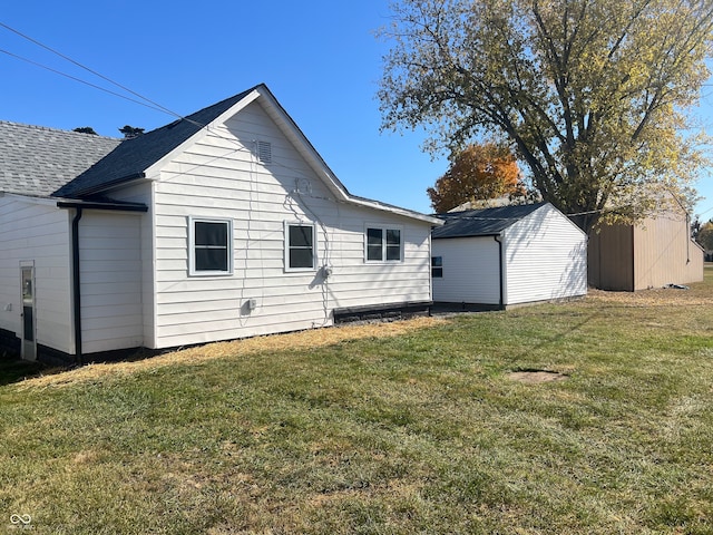 rear view of house with a lawn and a storage unit