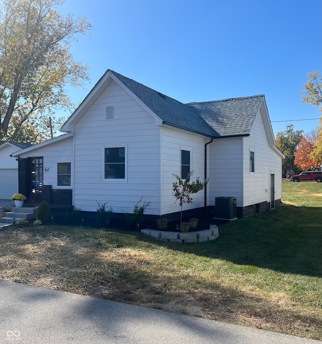 view of side of property with central AC unit and a yard