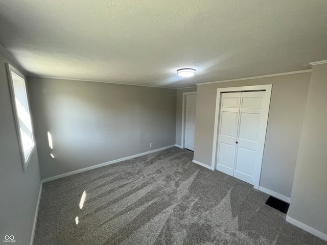 unfurnished bedroom featuring a textured ceiling, a closet, and dark colored carpet