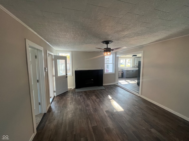 unfurnished living room with dark wood-type flooring, ornamental molding, a healthy amount of sunlight, and ceiling fan