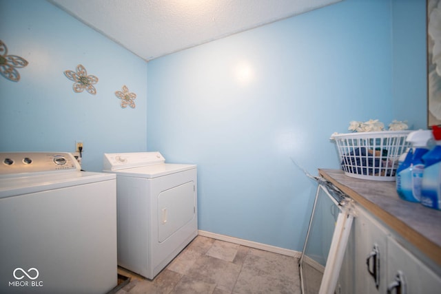 clothes washing area with a textured ceiling, washing machine and dryer, and cabinets