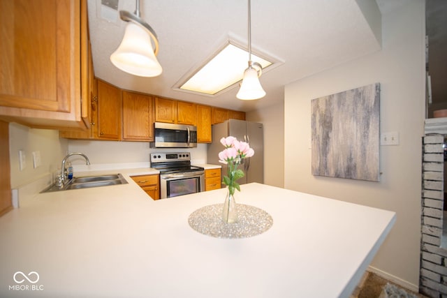 kitchen featuring pendant lighting, kitchen peninsula, stainless steel appliances, and sink