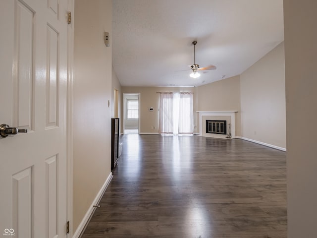 unfurnished living room with dark wood-type flooring, ceiling fan, a textured ceiling, and vaulted ceiling