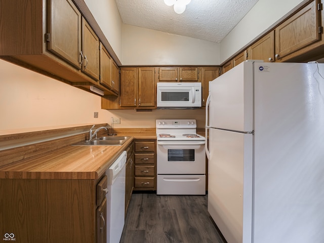 kitchen featuring sink, dark hardwood / wood-style floors, a textured ceiling, white appliances, and vaulted ceiling