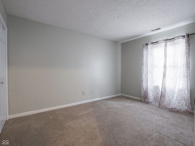 carpeted empty room featuring a textured ceiling