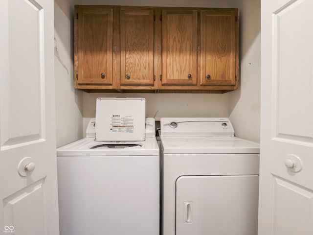 clothes washing area with separate washer and dryer and cabinets