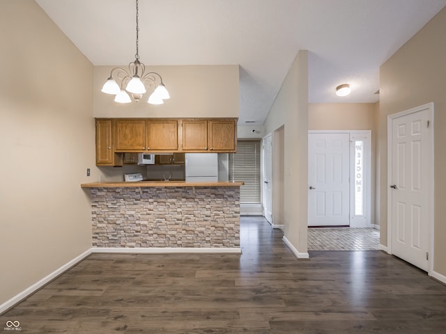 kitchen featuring hanging light fixtures, white fridge, dark wood-type flooring, and kitchen peninsula