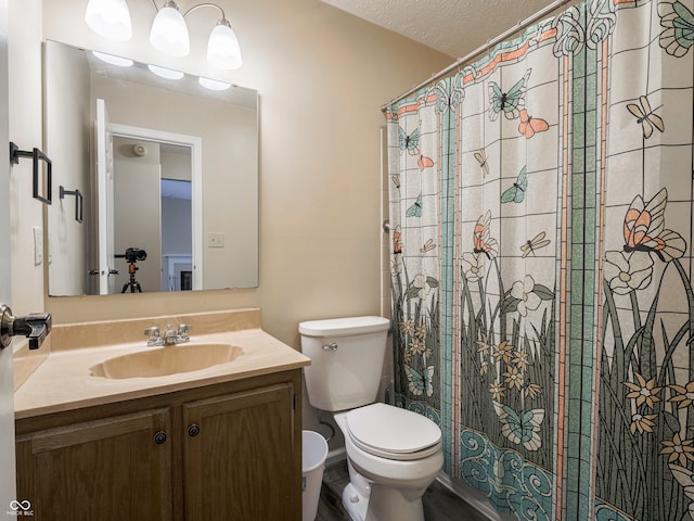 bathroom with toilet, vanity, a textured ceiling, and curtained shower