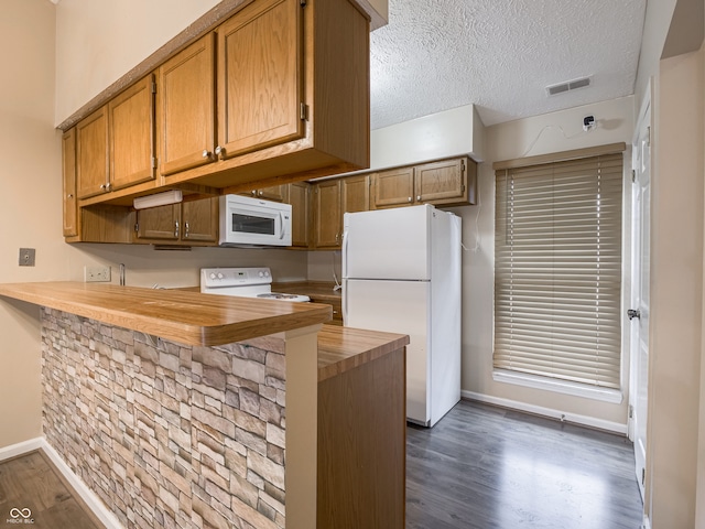 kitchen featuring dark hardwood / wood-style flooring, kitchen peninsula, a textured ceiling, wood counters, and white appliances