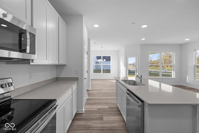 kitchen featuring white cabinetry, a center island with sink, stainless steel appliances, and sink