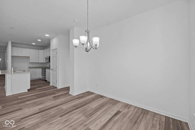 unfurnished dining area with hardwood / wood-style floors, a chandelier, and sink