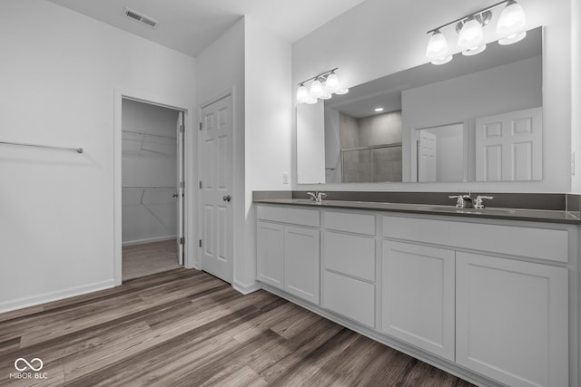 bathroom featuring hardwood / wood-style floors, walk in shower, and vanity