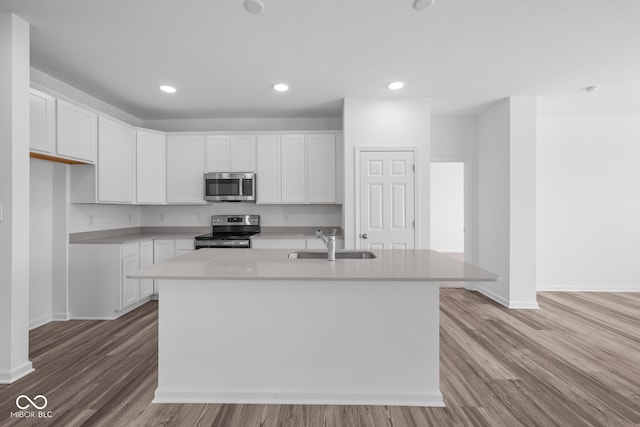 kitchen with appliances with stainless steel finishes, sink, a center island with sink, and white cabinets