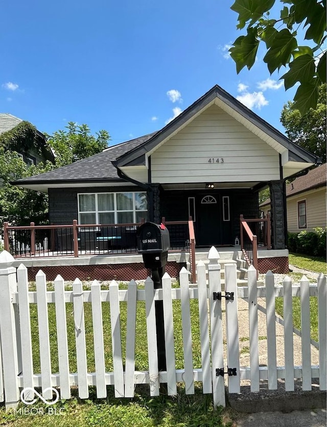 view of front facade featuring covered porch, driveway, and a fenced front yard