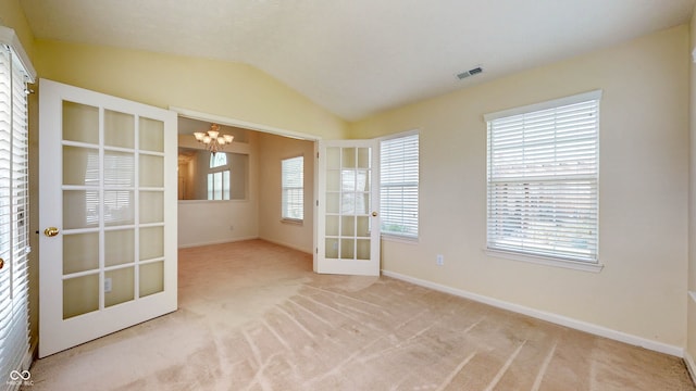 carpeted spare room with french doors, a healthy amount of sunlight, and a chandelier